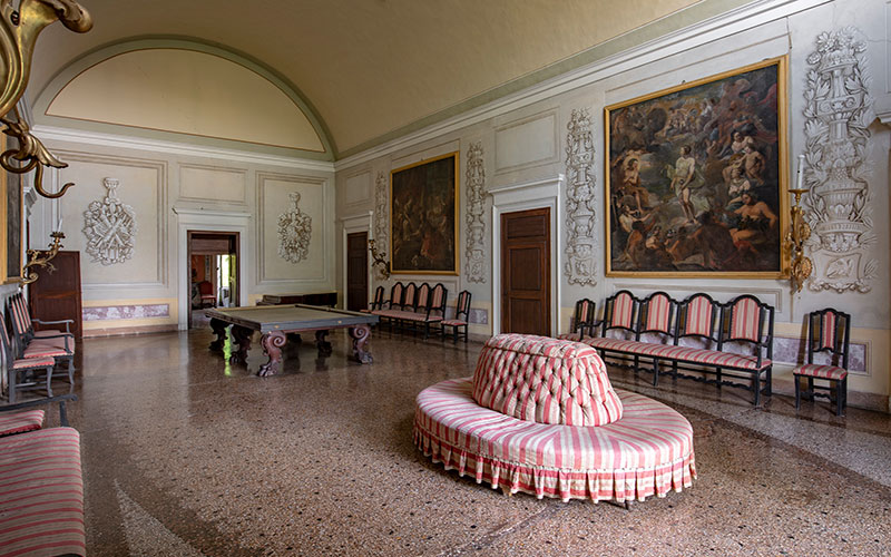 Villa Malaspina interno. Sala del biliardo con sedie e divano circolare.